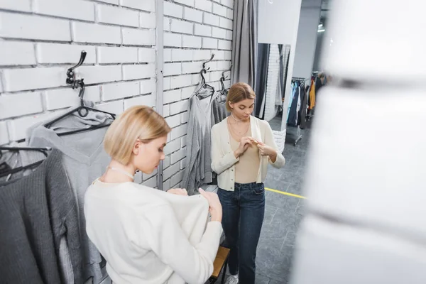 High angle view of woman looking at jumper near mirror in second hand — Photo de stock