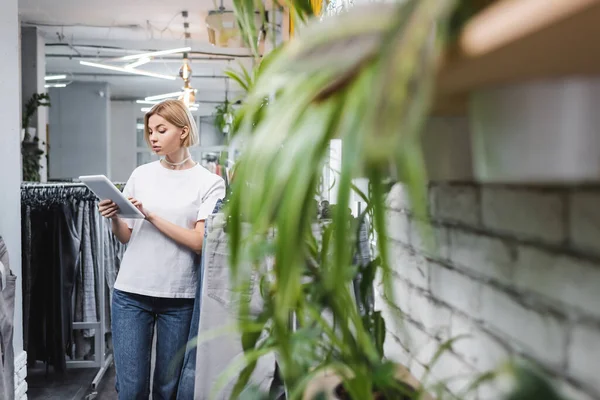 Blonde saleswoman using digital tablet in vintage shop — Stock Photo