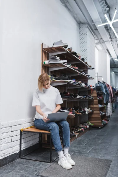 Blonde saleswoman using laptop in second hand — Fotografia de Stock