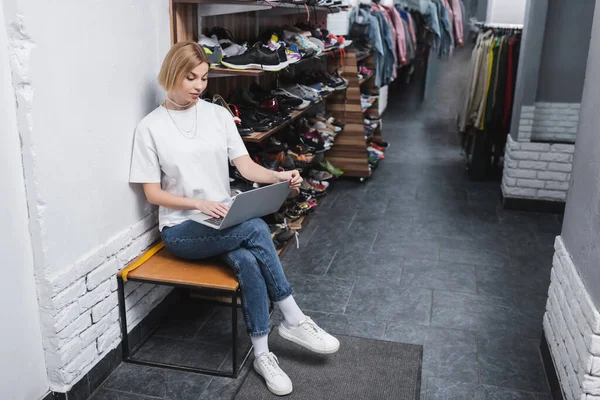 Blonde Einzelhändlerin benutzt Laptop in der Nähe von Schuhen in Vintage-Shop — Stockfoto