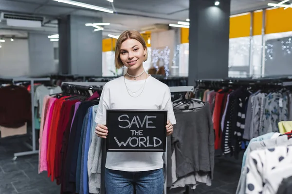 Lächelnde Verkäuferin mit Rettet-die-Welt-Schriftzug aus zweiter Hand — Stockfoto