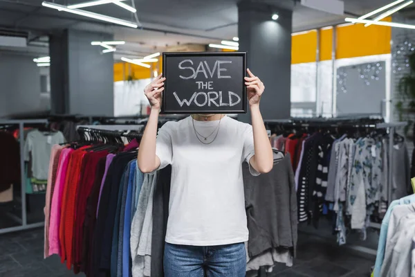 Retailer holding board with save the world lettering in second hand — стоковое фото