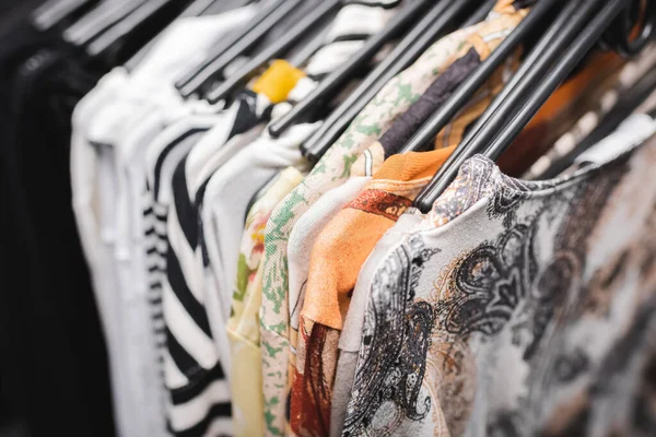 High angle view of vintage blouses on black hangers in second hand - foto de stock