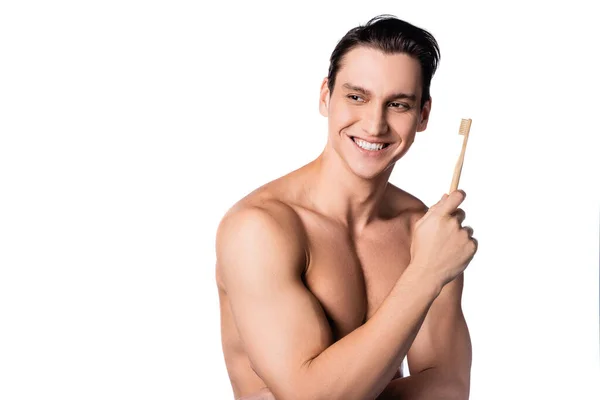 Uomo muscoloso senza maglietta con spazzolino da denti sorridente e distogliendo lo sguardo isolato sul bianco — Foto stock