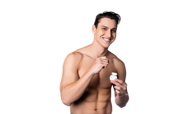 Uomo senza maglietta con forte corpo che tiene filo interdentale e sorridente alla fotocamera isolata su bianco — Foto stock