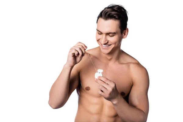 Morena sin camisa hombre sonriendo mientras sostiene hilo dental aislado en blanco - foto de stock
