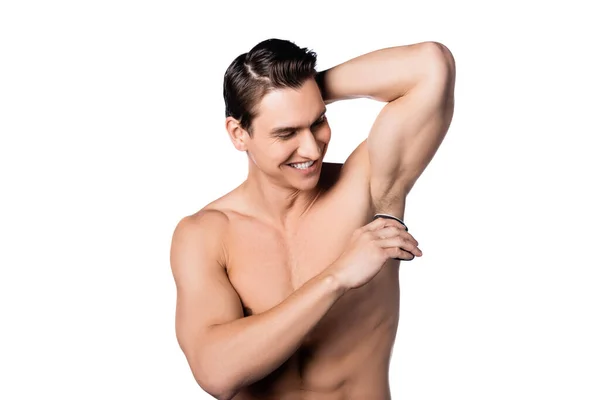 Cheerful shirtless man applying antiperspirant on armpit isolated on white — Stock Photo