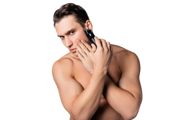 Shirtless man shaving with electric trimmer while looking at camera isolated on white — Stock Photo