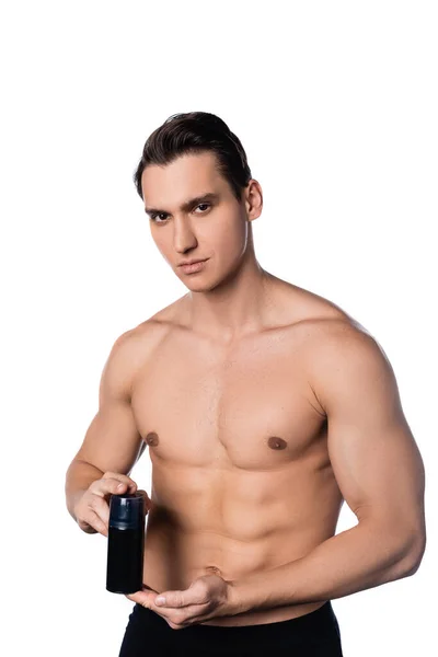 Hombre con cuerpo muscular sosteniendo desodorante y mirando a la cámara aislada en blanco - foto de stock