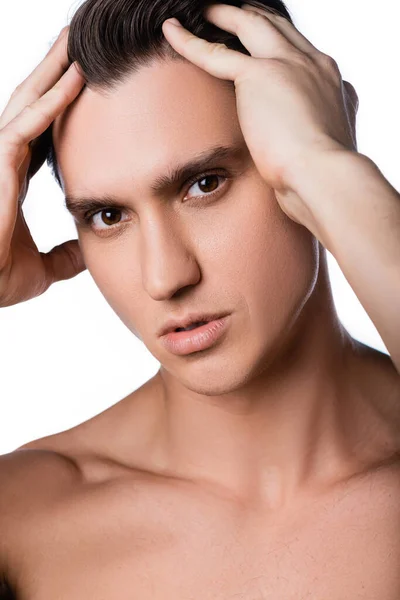 Portrait of man with perfect face touching hair and looking at camera isolated on white — Stock Photo