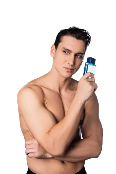 Morena hombre sin camisa con botella de perfume mirando hacia otro lado aislado en blanco - foto de stock