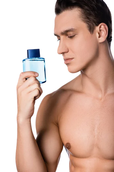 Брюнетка чоловік з голими грудьми тримає після гоління лосьйон ізольовано на білому — стокове фото