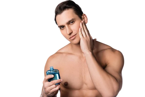 Morena hombre con pecho desnudo aplicando después de afeitarse loción y mirando a la cámara aislada en blanco — Stock Photo