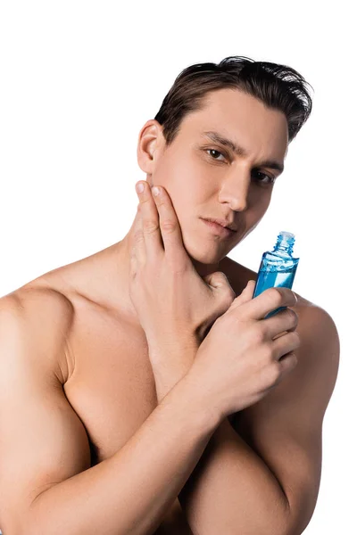 Brunette man with naked shoulders applying after shave lotion isolated on white — Stock Photo
