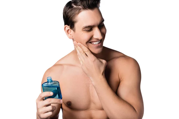Homem shirtless alegre aplicando após loção de barbear na bochecha isolada no branco — Fotografia de Stock