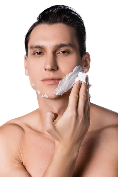 Hombre con pecho desnudo aplicando espuma de afeitar mientras mira la cámara aislada en blanco - foto de stock