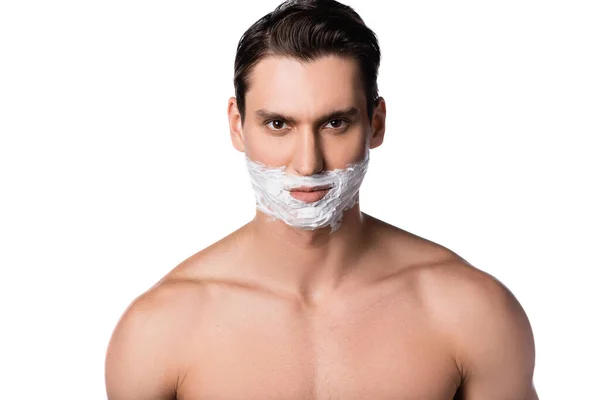 Morena hombre con hombros desnudos y espuma de afeitar en la cara mirando a la cámara aislada en blanco - foto de stock