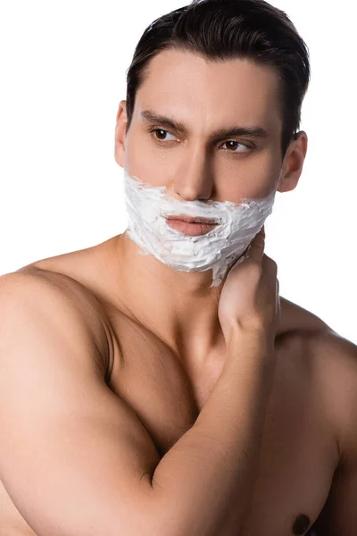 Man with naked shoulders and shaving foam on face looking away isolated on white — Stock Photo