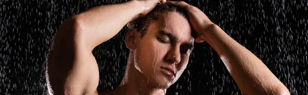 Mann mit Händen am Kopf beim Duschen mit geschlossenen Augen auf schwarzem Hintergrund, Banner — Stockfoto