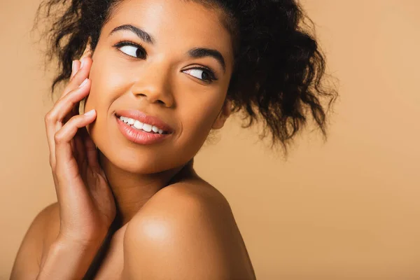 Portrait of young african american woman with bare shoulders and perfect skin isolated on beige — Stock Photo