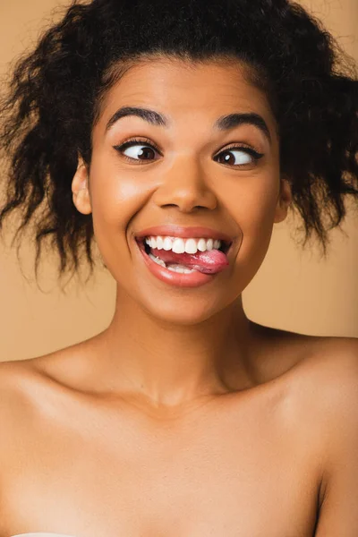 Ricci donna africana americana con spalle nude sporgenti lingua isolata sul beige — Foto stock