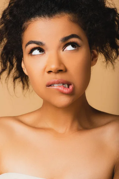 Thoughtful african american woman with bare shoulders looking away isolated on beige — Stock Photo