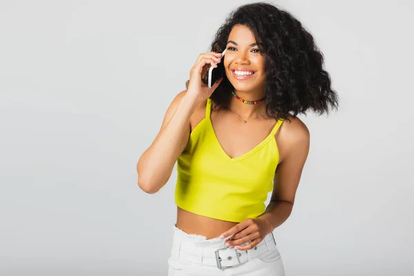 Щаслива афроамериканська жінка говорить на смартфоні ізольовано на сірому — стокове фото