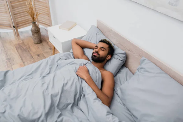 Blick aus der Vogelperspektive auf einen jungen afrikanisch-amerikanischen Mann, der im Bett schläft — Stockfoto