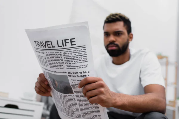 Hombre afroamericano serio con la barba leyendo el periódico de la vida de viaje - foto de stock