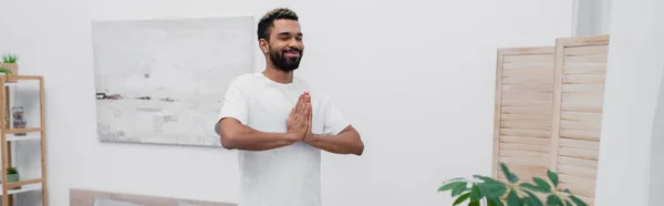 Homem americano africano feliz homem americano africano meditando com as mãos orando perto de tela dobrável, bandeira — Fotografia de Stock