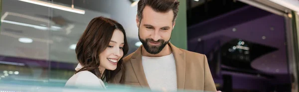 Cheerful couple looking away in jewelry shop, banner - foto de stock