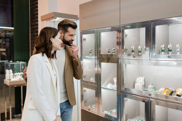 Pensive man hugging girlfriend near jewelry in shop — Foto stock