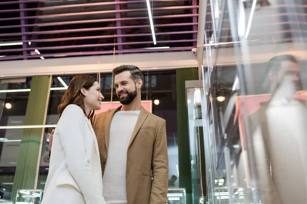 Vista a basso angolo dei clienti che sorridono vicino alla vetrina in gioielleria — Foto stock