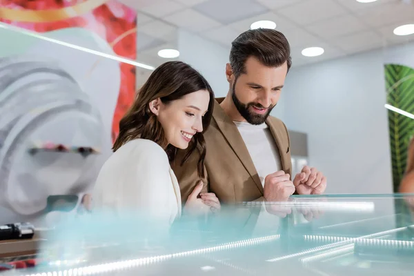 Fröhliche Kunden blicken auf verschwommene Vitrine in Schmuckgeschäft — Stockfoto