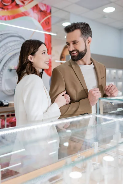 Smiling buyers looking at each other near showcase in jewelry store — Stock Photo