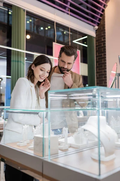 Pensive man looking at jewelry near girlfriend in store — Stock Photo