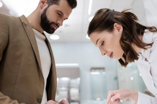 Seller and customer looking down while choosing in jewelry shop — Stock Photo