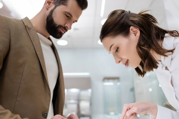 Vendedor y cliente mirando hacia abajo al elegir en la joyería - foto de stock