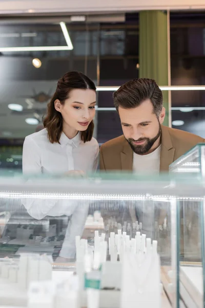 Bearded customer and smiling seller choosing jewelry in shop — Stock Photo