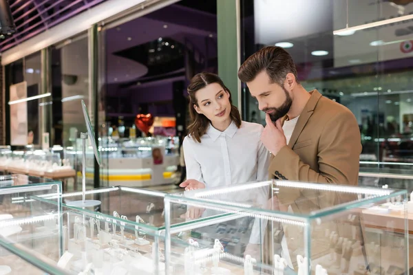 Seller pointing at showcase near pensive customer in jewelry shop — Stock Photo