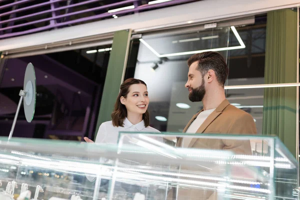 Seller talking to buyer near blurred glass showcase in jewelry shop — Stock Photo