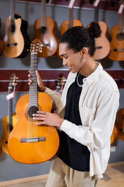 Side view of african american customer holding acoustic guitar in music store — Photo de stock