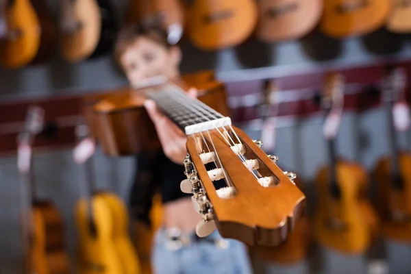 Guitare acoustique et client flou dans le magasin de musique — Photo de stock