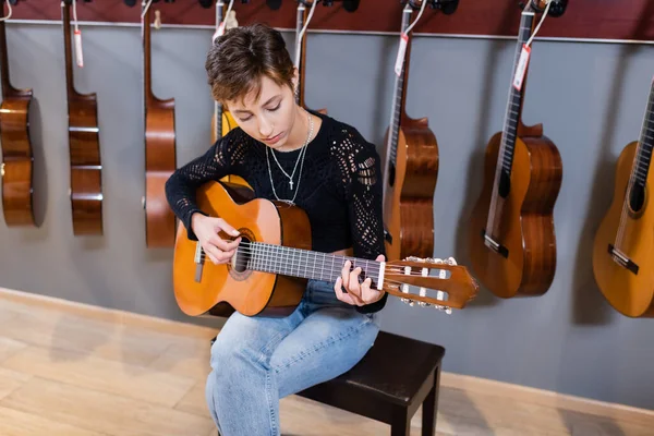 Musician playing acoustic guitar in music store — Stockfoto