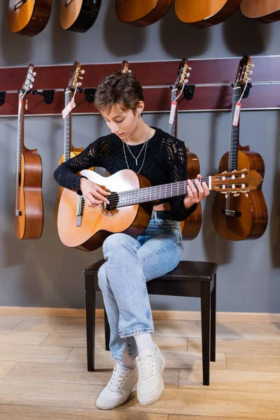 Kundin spielt Akustikgitarre im Musikladen — Stockfoto