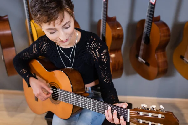 Smiling buyer playing acoustic guitar in music shop — Foto stock