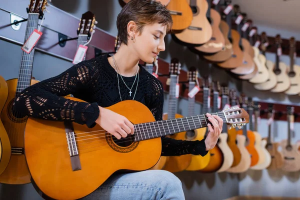 Vista laterale del cliente che suona la chitarra acustica nel negozio di musica strumentale — Foto stock