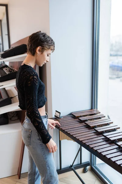 Side view of customer standing near xylophone in music store - foto de stock