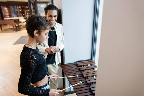 Customer playing xylophone near african american seller in music shop — Stock Photo