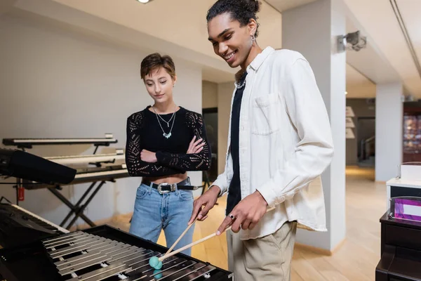 Cheerful african american seller playing xylophone near young customer in music store — Stockfoto